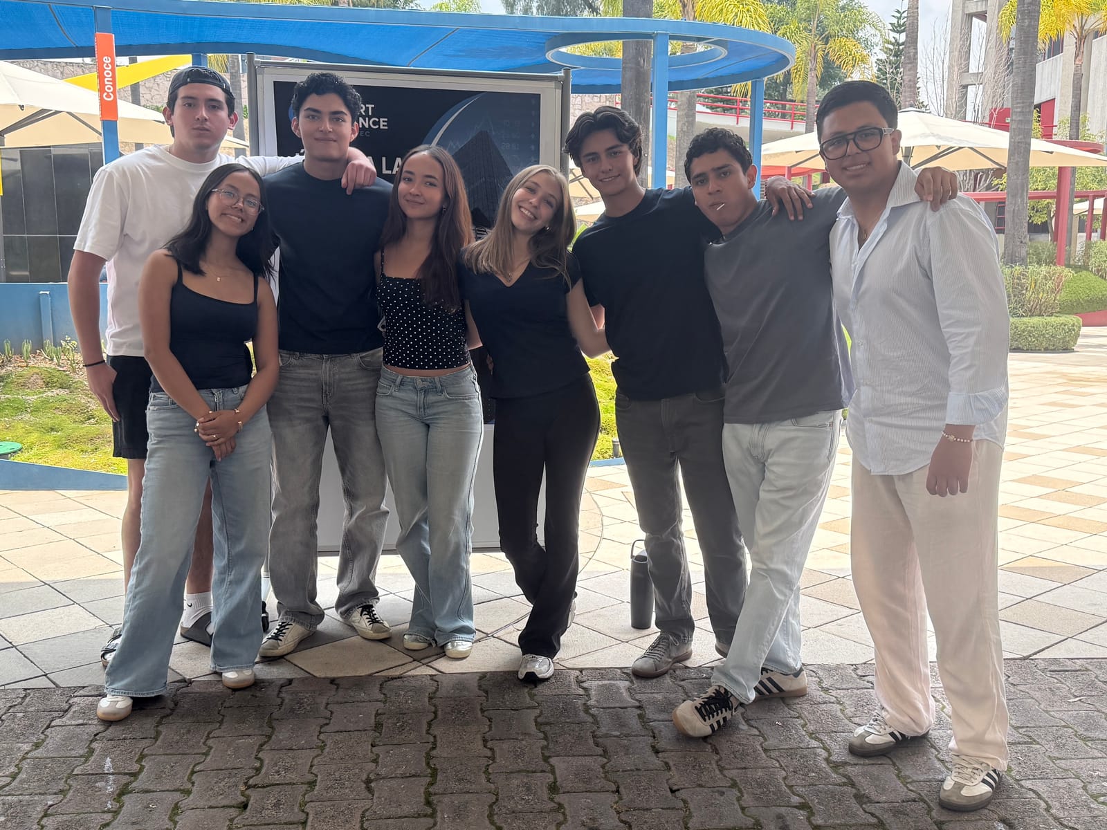 The eight members of the Smart Finance student group standing in front of the club banner, on campus